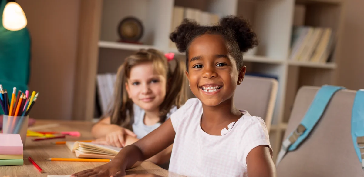 Two elementary students doing homework together and smiling at the camera