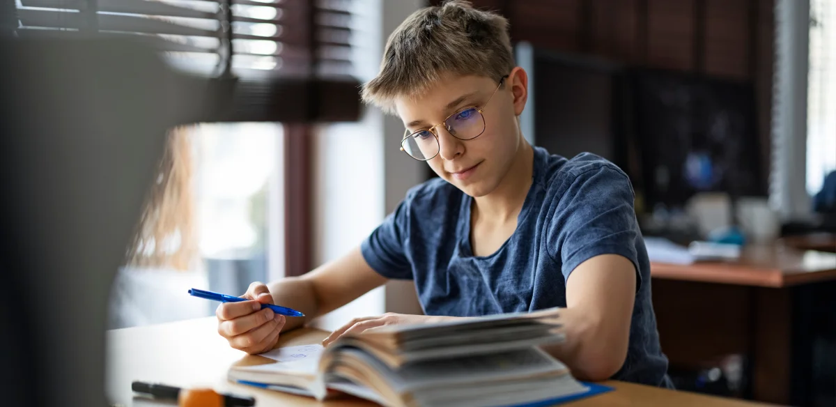 Middle school student reading and taking notes at home